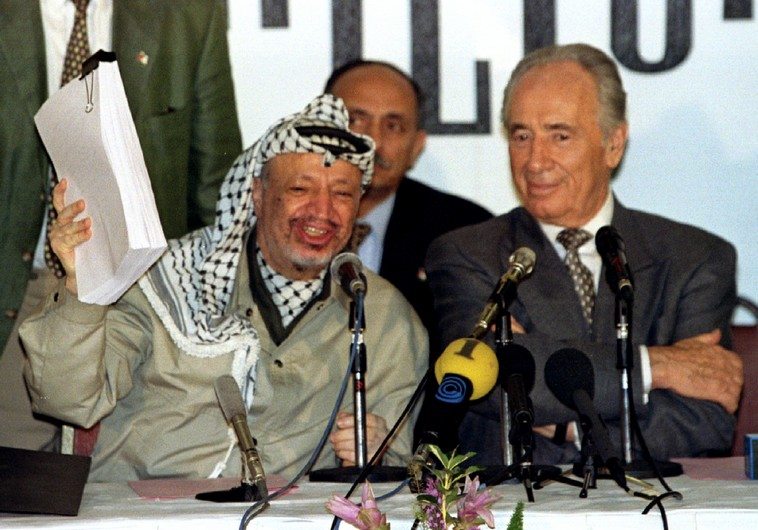 PLO chairman Yasser Arafat holds the second phase of the Oslo peace accords after the initialling of..
